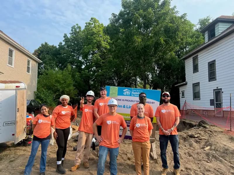 L'équipe de bénévoles de Qualitrol portant des chemises orange sur le site de construction de Habitat for Humanity