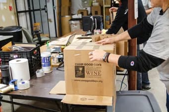 Bénévoles de Qualitrol emballant des cartons de dons sur une table